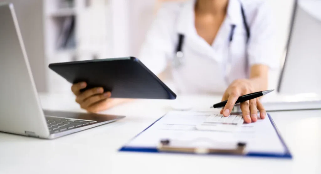 Image of a doctor sitting at a desk looking at a medical chart