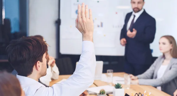 image of a man raising his hand to ask a question in a conference room