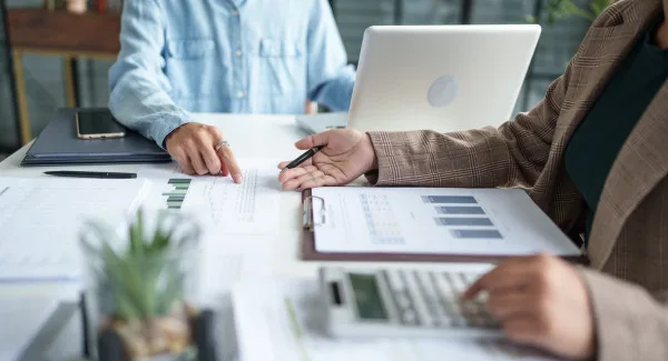 Image of paperwork on a table with two people gesturing towards the data on the paperwork