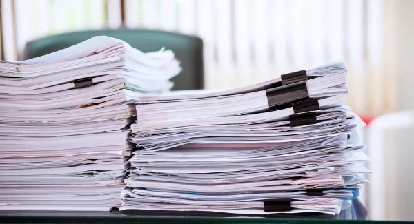 Two stacks of files sitting on desk next to one another