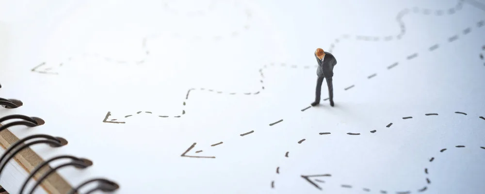 A piece of paper with multiple different routes drawn on, and a man deciding which route to follow
