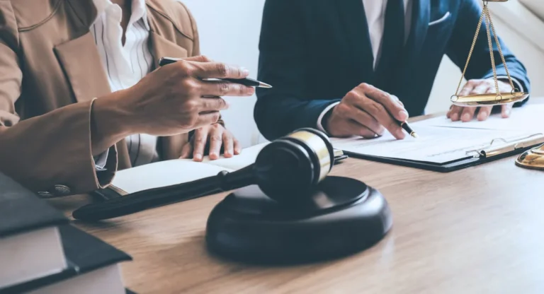Image of a gavel and two people reviewing documents at a desk